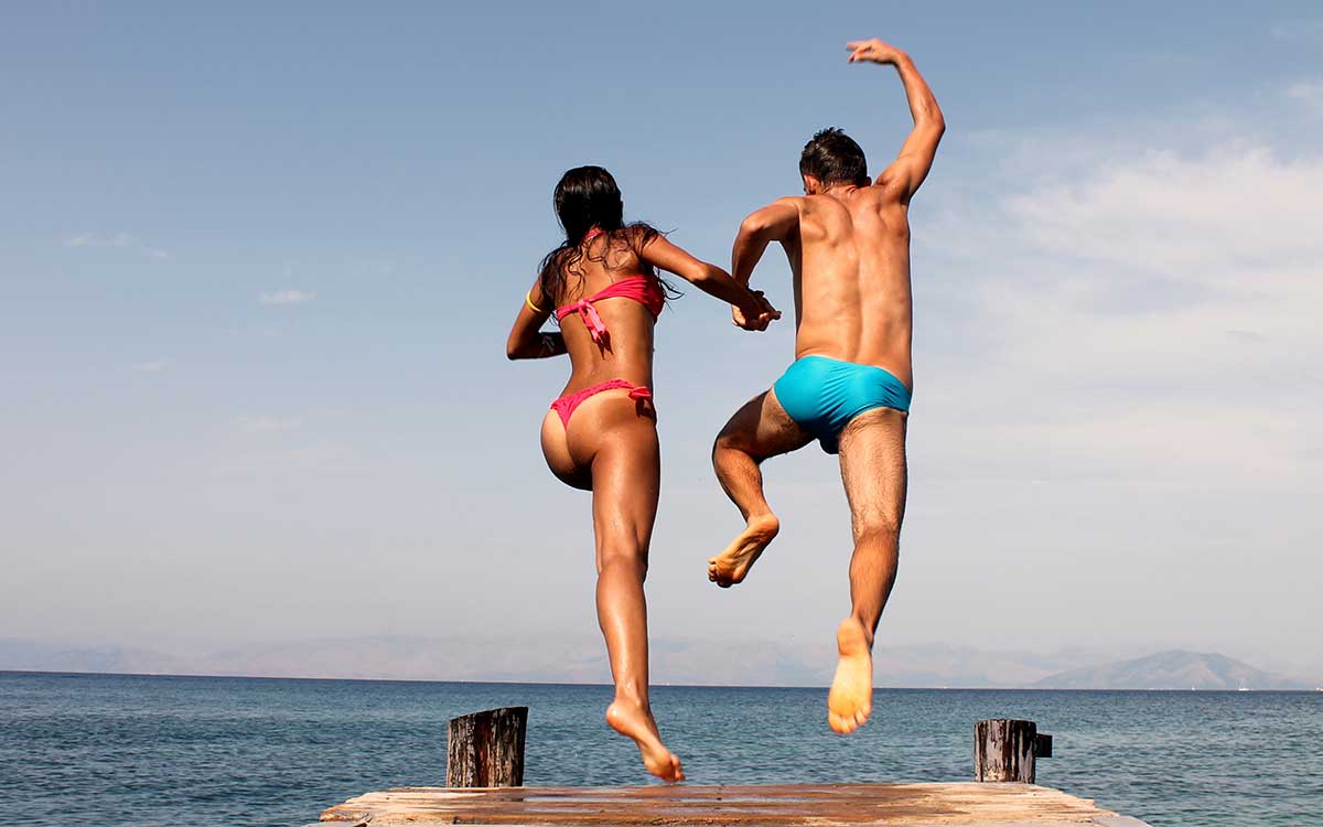 Couple jumping from the pier